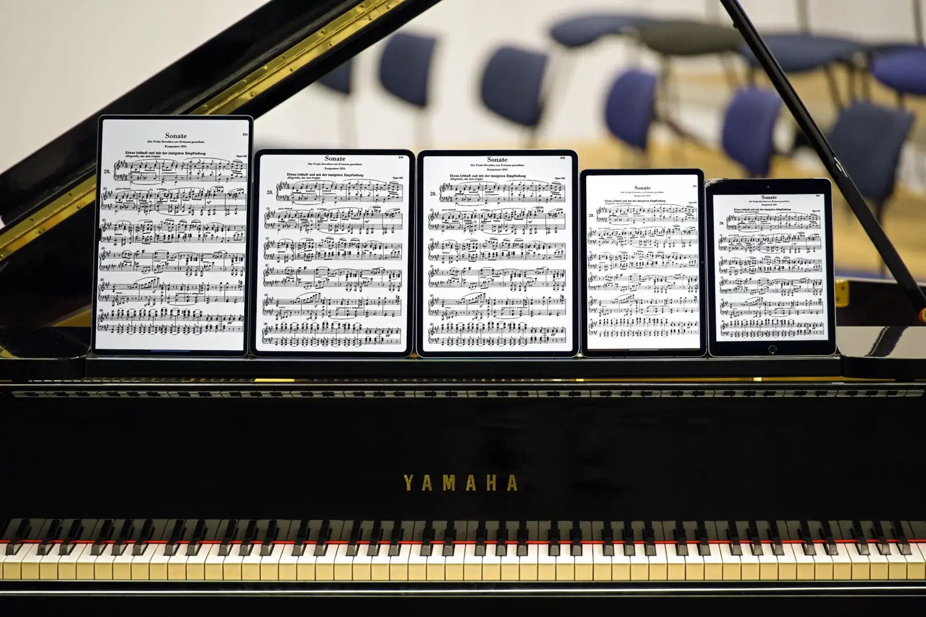 Sheet music displayed on five iPads and tablets on a piano